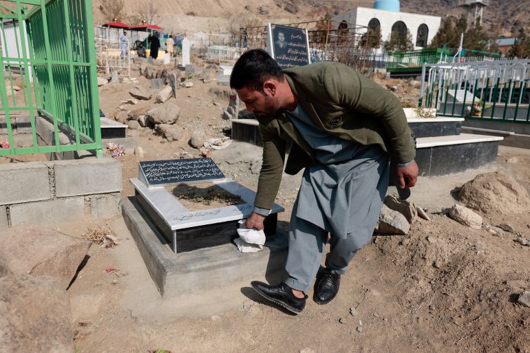 Emal Ahmadi cleans the grave of his daughter Malika, who was a victim of a U.S drone strike
