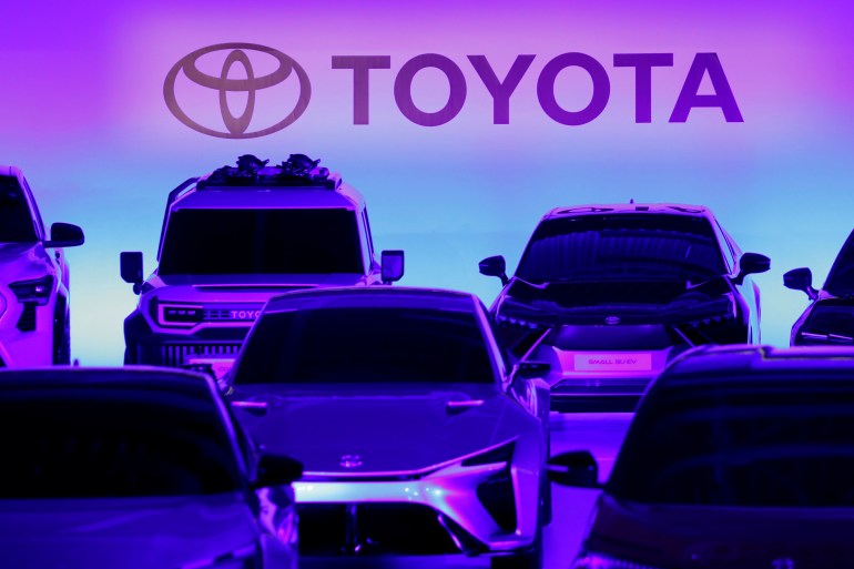 Toyota cars are parked in front of the company's logo