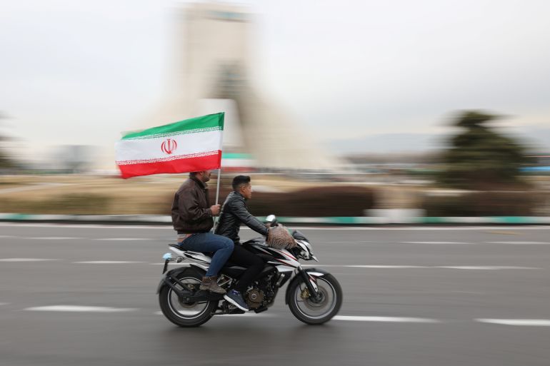 Iranians ride on a motorcycle during celebration of the 43rd anniversary of the Islamic Revolution in Tehran, Iran, February 11, 2022.