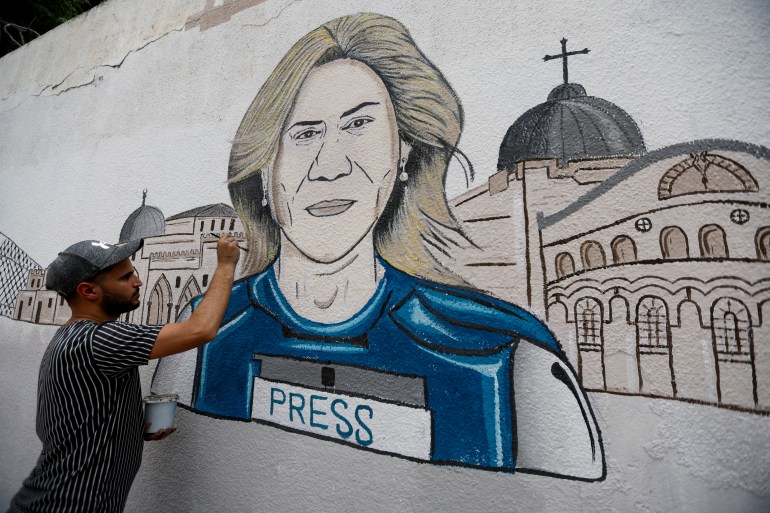 Een man neemt deel aan het tekenen van een muurschildering van Al Jazeera-journalist Shireen Abu Akleh, gedood tijdens een Israëlische inval op de door Israël bezette Westelijke Jordaanoever, in Khan Younis, in de zuidelijke Gazastrook, op 14 mei 2022.