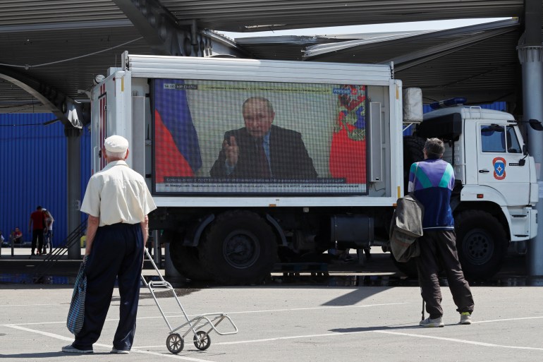 Russian President Vladimir Putin is seen on a screen broadcasting Russian TV news programs at a humanitarian aid distribution point during Ukraine-Russia conflict in the southern port city of Mariupol, Ukraine May 30, 2022. REUTERS/Alexander Ermochenko