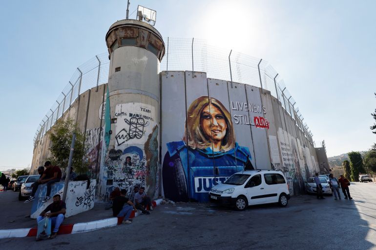 Palestinians sit in front of a mural depicting the slain Palestinian-American journalist Shireen Abu Akleh ahead of the visit of U.S. President Joe Biden at Bethlehem in the Israeli-occupied West Bank July 13, 2022.