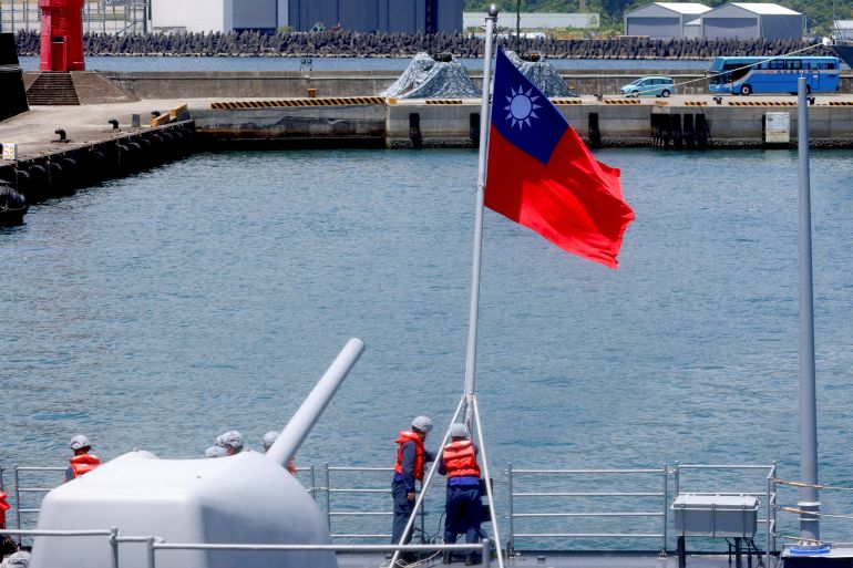 Members of the navy put up a Taiwanese flag as the naval vessel approaches the port in Yilan, Taiwan, in 2022 [Ann Wang/Reuters]