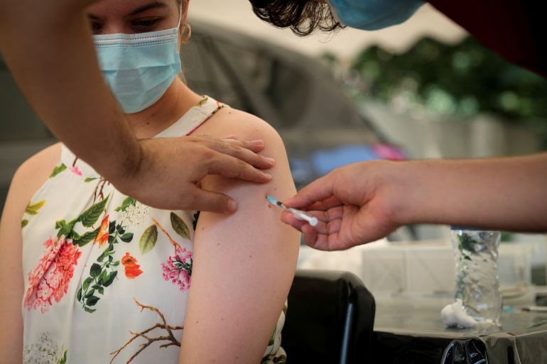A healthcare worker administers the coronavirus vaccine to a woman.