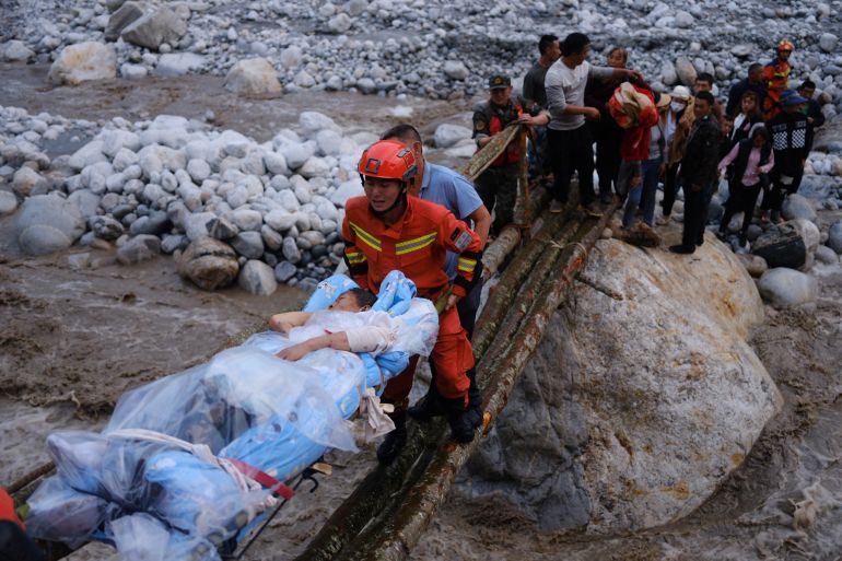 Rescue workers carry an injured victim on a stretcher following a 6.8-magnitude earthquake in Qinggangping village, Luding county, Sichuan province, China.