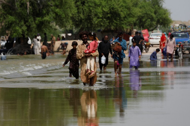 Residents walk amid flood water as they head to their villages, following rains and floods during the monsoon season in Sehwan, Pakistan September 6, 2022.