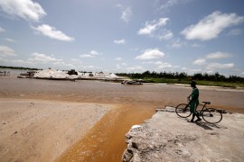 A man stands while watching the breach created by flood water that washed away salt mounts on the bank of the Lac Rose also known as Lake Retba in Niaga, near Dakar, Senegal