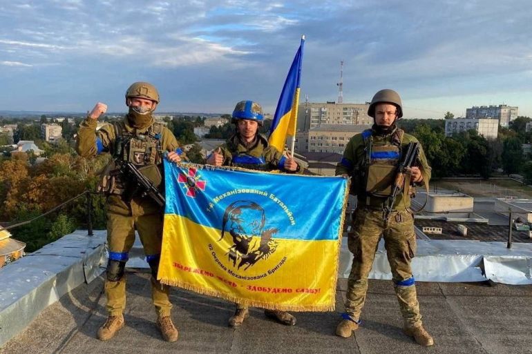 Ukrainian soldiers hold a flag
