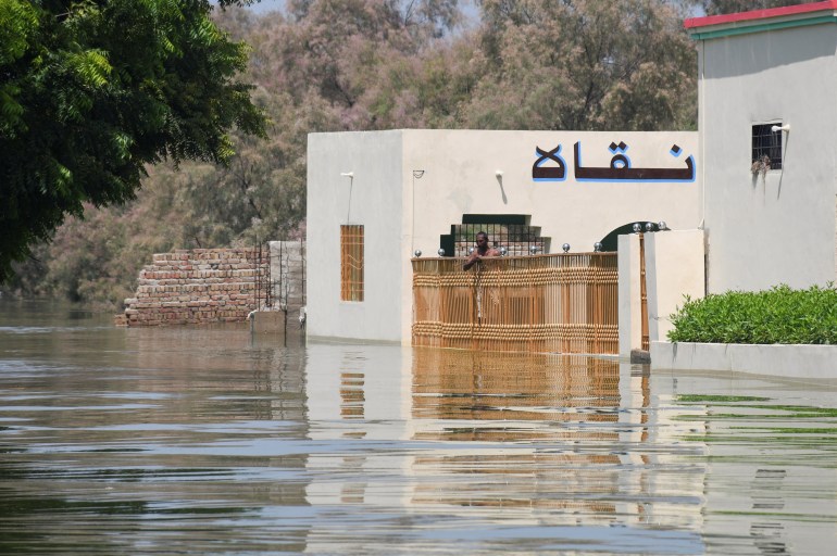 A man stands at the main entrance of a building amid floodwater, following rains and floods during the monsoon season in village Arazi, in Sehwan, Pakistan September 11, 2022.