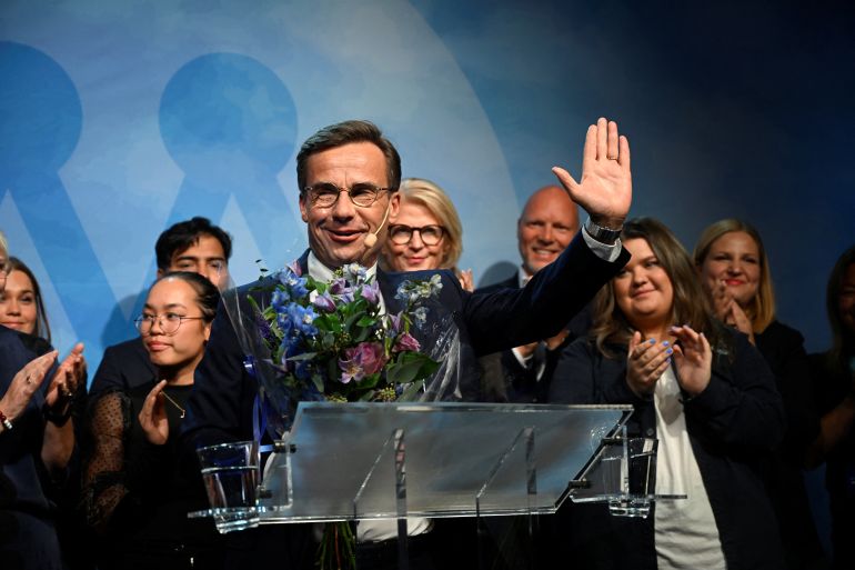 Moderate party leader Ulf Kristersson waves to supporters from the stage, backed by party members clapping