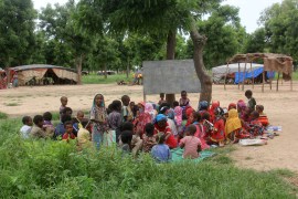 A photo of children sitting under a shade in an open-air classroom in Chad