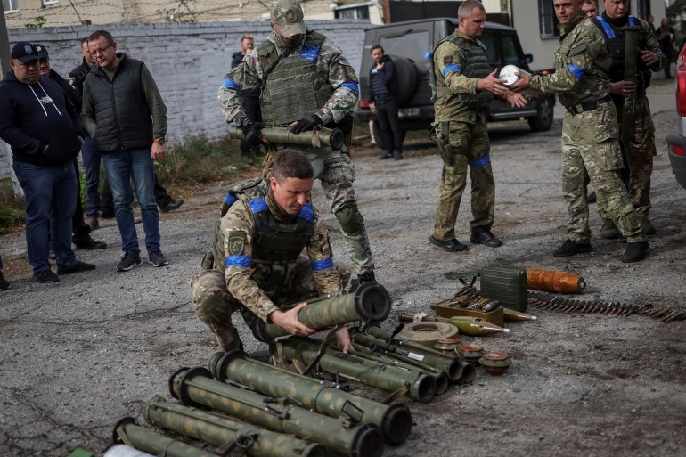 A police sapper sorts unexploded mine shells and weapons after return from the village of Udy, recently liberated by Ukrainian