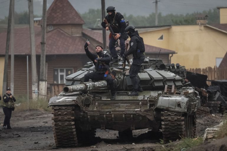 Police officers take a selfie on a destroyed Russian tank, as Russia's attack on Ukraine continues, in the town of Izium, recently liberated by Ukrainian Armed Forces, in Kharkiv region, Ukraine September 14, 2022. REUTERS/Gleb Garanich