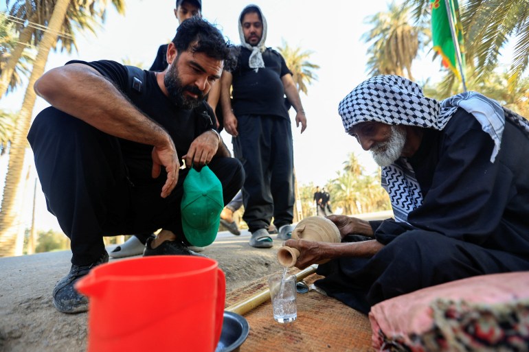 An Iraqi volunteer pours water for Shi'ite Muslim pilgrims 