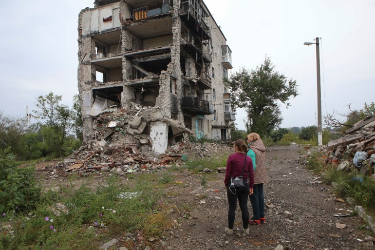 Women stand near a residential building destroyed by a military strike in the town of Izium recently liberated by the Ukrainian Armed Forces during a counteroffensive operation, amid Russia's attack on Ukraine, in Kharkiv region, Ukraine September 15, 2022. REUTERS/Vyacheslav Madiyevskyy