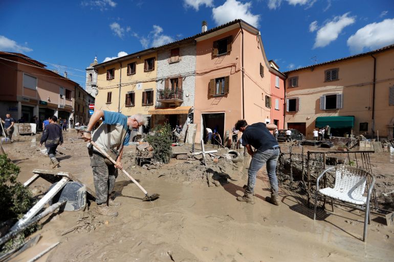 People work to clear debris way after heavy rain and deadly floods hit the central Italian region of Marche