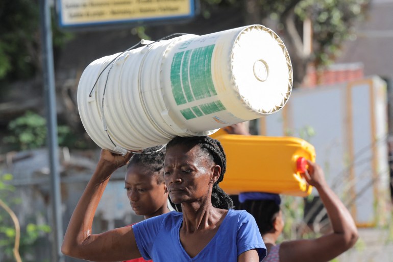 Women carry containers to be filled with water amid shortages of water, cooking gas and other items after days of protest forced them to shelter at home, in Port-au-Prince, Haiti September 17, 2022.