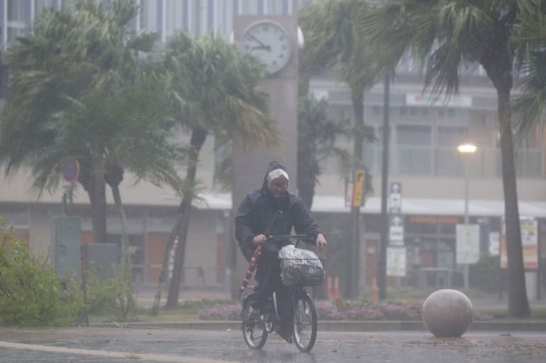 A man on a bicycle rides past in the heavy rain and wind caused by Typhoon Nanmadol in Miyazaki on Japan's southernmost main island of Kyushu September 18, 2022