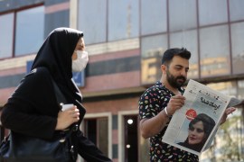 A man views a newspaper with a cover picture of Mahsa Amini, a woman who died after being arrested by the Islamic republic's "morality police"