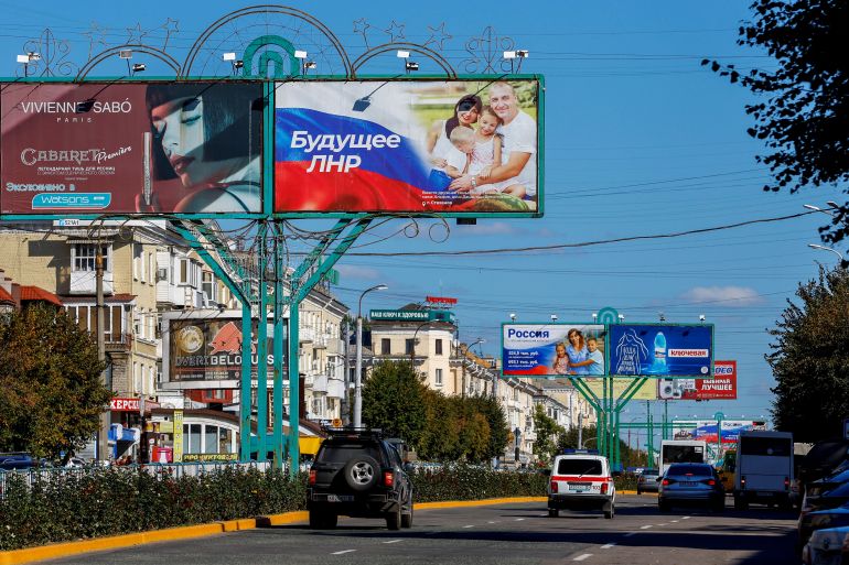 Vehicles drive past advertising boards, including panels displaying pro-Russian slogans, in a street in the course of Russia-Ukraine conflict in Luhansk, Ukraine, September 20, 2022.