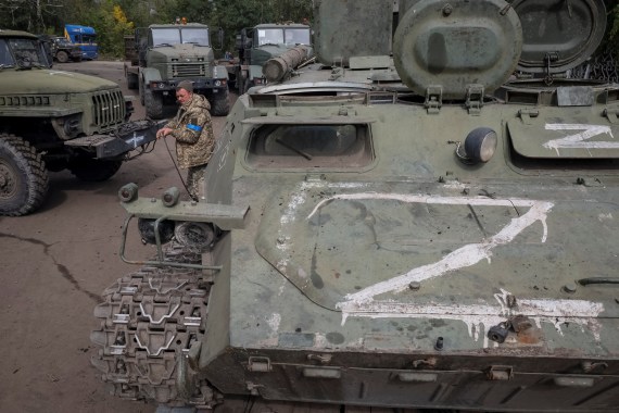 Um soldado ucraniano se prepara para rebocar um transportador de pessoal blindado russo destruído