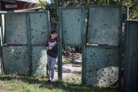 A ukrainian girl stands on a gate with holes created by shrapnel near her house, as Russia's attack on Ukraine continues, in the village of Savyntsi, recently liberated by Ukrainian Armed Forces, in Kharkiv region, Ukraine September 21, 2022. REUTERS/Gleb Garanich