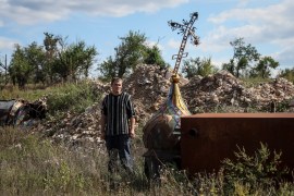 Local resident Yuriy Zdorovets, 42, looks at a cross from a destroyed church in the village of Kamyanka, recently liberated by Ukrainian Armed Forces, in Kharkiv region, Ukraine September 22, 2022. REUTERS/Gleb Garanich
