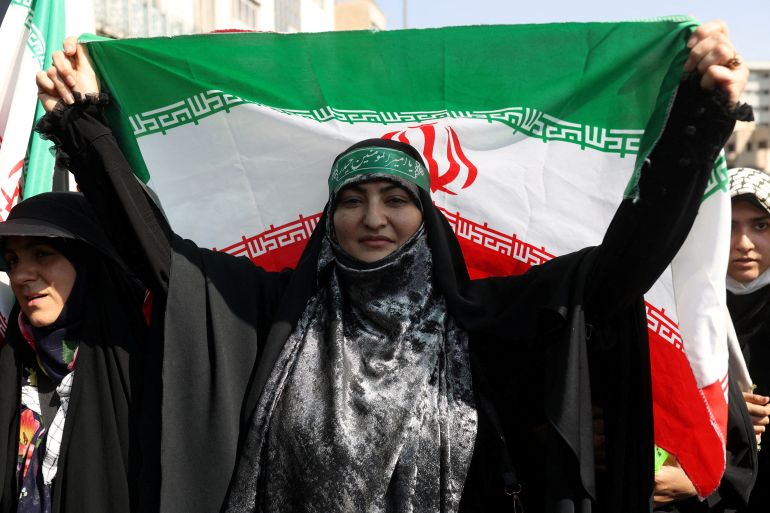 Iranian woman in chador holds up the iranian flag at a protest