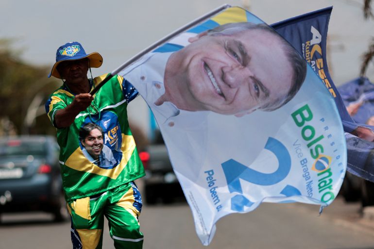 Bolsonaro supporter carries an electoral banner emblazoned with an image of Brazil's President Jair Bolsonaro while campaigning in Brasilia, Brazil September 24, 2022.
