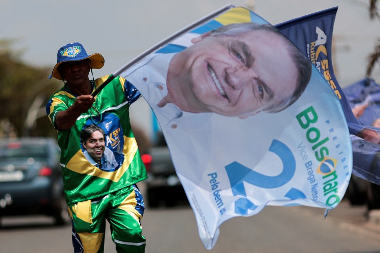 Bolsonaro supporter carries an electoral banner emblazoned with an image of Brazil's President Jair Bolsonaro while campaigning in Brasilia, Brazil September 24, 2022.