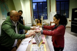 An election worker hands out a ballot to a voter during the snap election, in Rome, Italy, September 25, 2022 [Guglielmo Mangiapane/ Reuters]