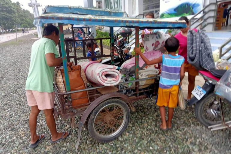 Residents carry belongings to evacuation centre in Aurora Province, Philippines