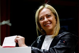 Giorgia Meloni, in a black leather jacket, smiles as she casts her vote