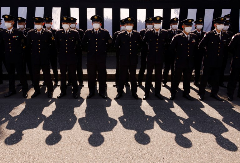 Members of Japan Self-Defense Forces stand in front of sacred funeral curtains creating shadows on the ground during a rehearsal for Abe's state funeral