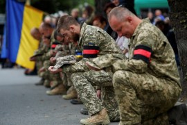 Ukrainian service members kneel during a funeral ceremony for their brother-in-arm Armen Petrosian, 50, who was recently killed in a fight against Russian troops during the liberation of Kharkiv region, amid Russia's attack on Ukraine, in Perechyn, Zakarpattia region, Ukraine September 25, 2022. REUTERS/Serhii Hudak