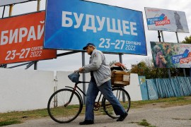 A man walks past banners informing about a referendum on the joining of Russian-controlled regions of Ukraine to Russia.