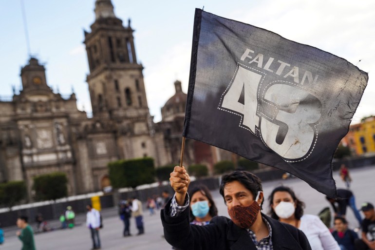 A man waves a flag reading, '43 are missing' during a march in Mexico City