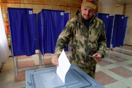 A service member of the self-proclaimed Donetsk People's Republic (DPR) casts his ballot at a polling station during a referendum on the joining of DPR to Russia