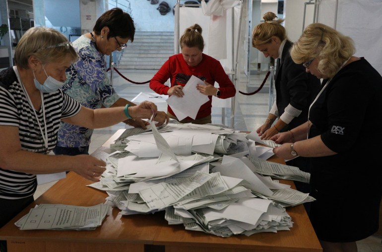 Mulheres contando votos de referendo em torno de uma mesa