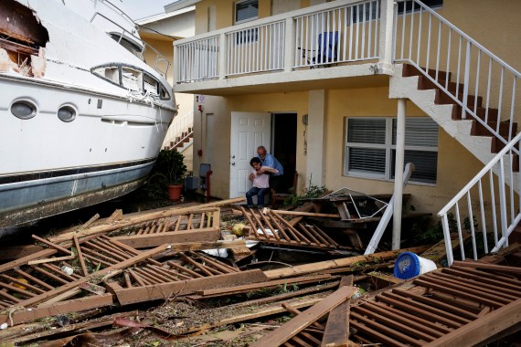 A man helps a woman next to a damaged boat strewn next to a condominium in Florida after Hurricane Ian.