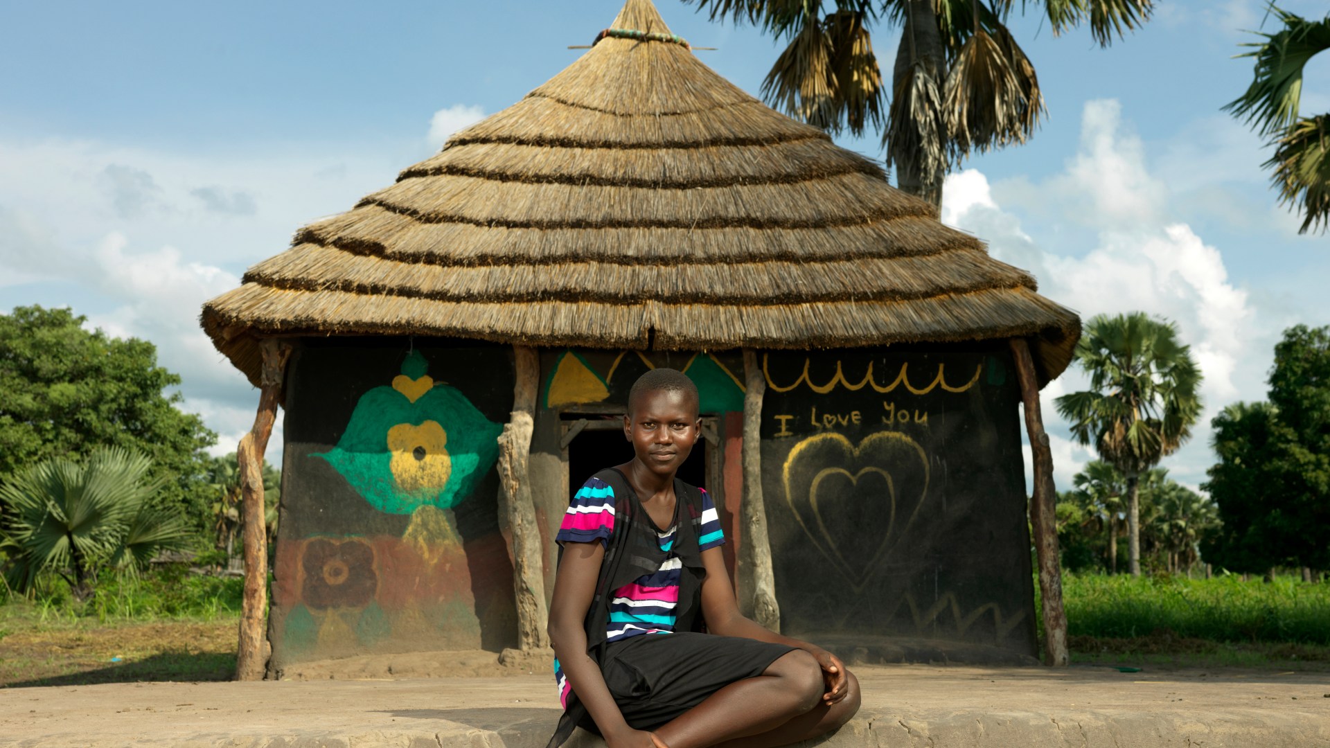 A photo of a girl sitting in front of a house.