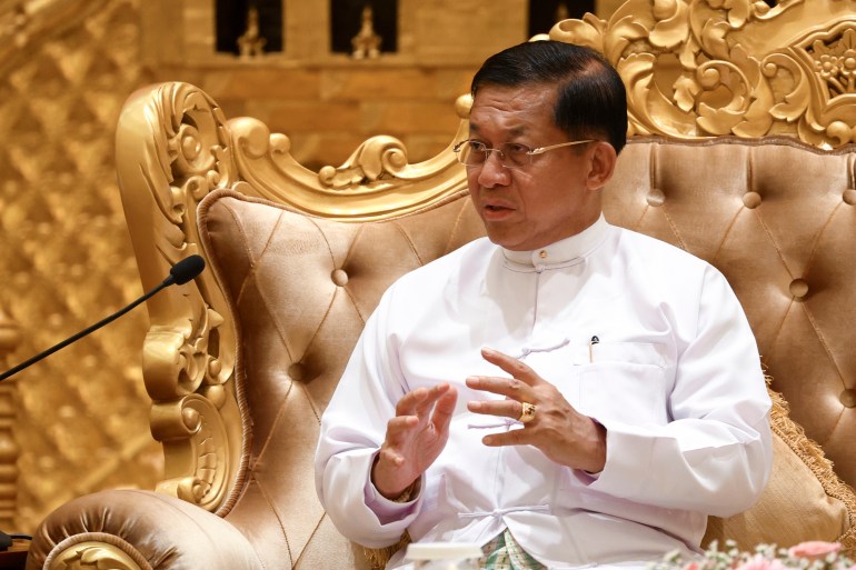 Min Aung Hlaing in white civilian clothes sitting in a large gilded chair while speaking to Russian Foreign Minister Sergey Lavrov