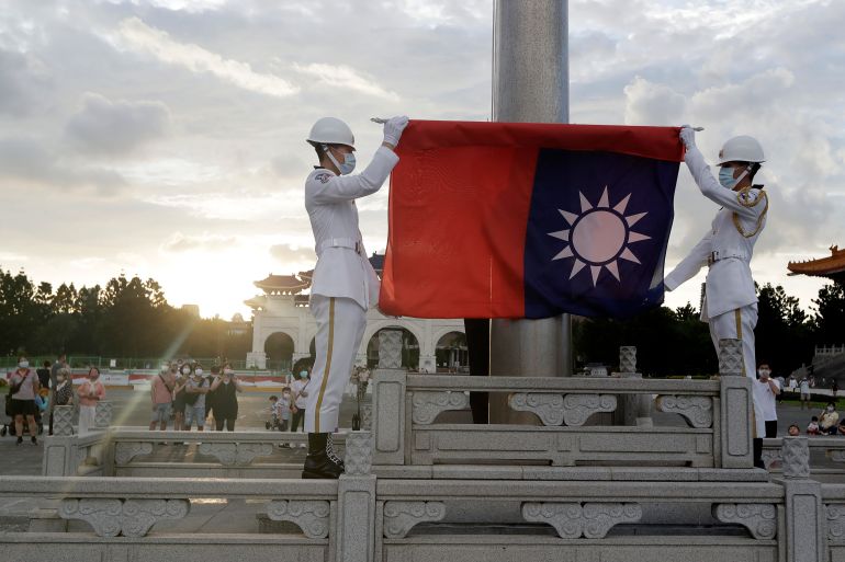 Two soldiers in white uniforms fold the national flag during the daily flag ceremony