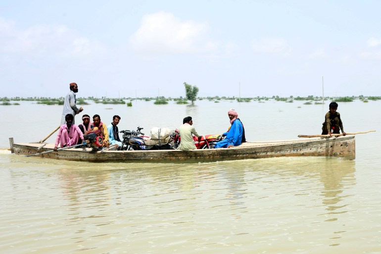 Pakistani men uses a boat to salvage usable items from their flood-hit homes in Dadu district of Sindh.