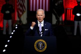 US President Joe Biden, speaking from behind a lectern, clenches his fist as he makes a point