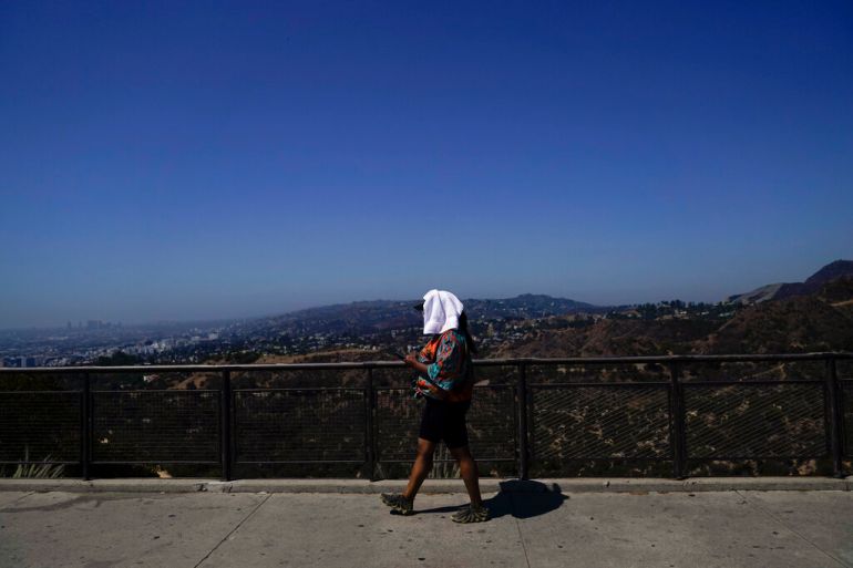 A tourist with a white towel on their head tries to stay cool in Los Angeles, California.