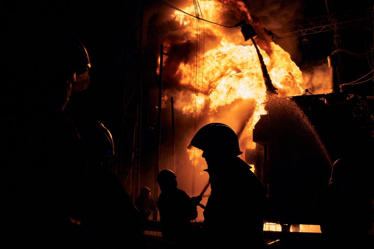 A fire fighter silhouetted against flames at a Kharkiv power station that was hit by a Russian rocket attack