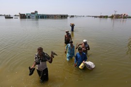 Victims of flooding from monsoon rains carry belongings salvaged from their flooded home in the Dadu district of Sindh Province, of Pakistan, September 9, 2022