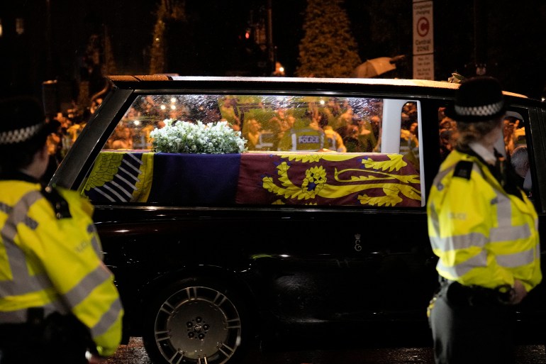 Sicriul drapat cu steagul reginei trece printr-o stradă mărginită de aglomerație din Londra, Marea Britanie.