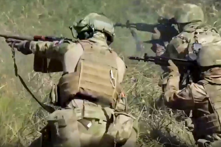 In this handout photo taken from video released by Russian Defense Ministry Press Service on Monday, Sept. 19, 2022, members of a special forces unit of the Russian army aim their weapons in action at an unspecified location in Ukraine.